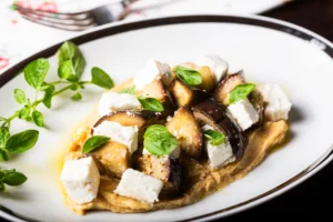 foto di piatto bilanciato di melanzane al vapore con feta su purea di ceci