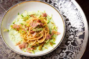 foto di primo piatto bilanciato con spaghetti integrale, crema di zuccine e chips di prosciutto crudo